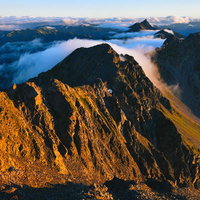 朝焼けに染まる奥穂高岳の山々と雲海、登山の絶景の写真