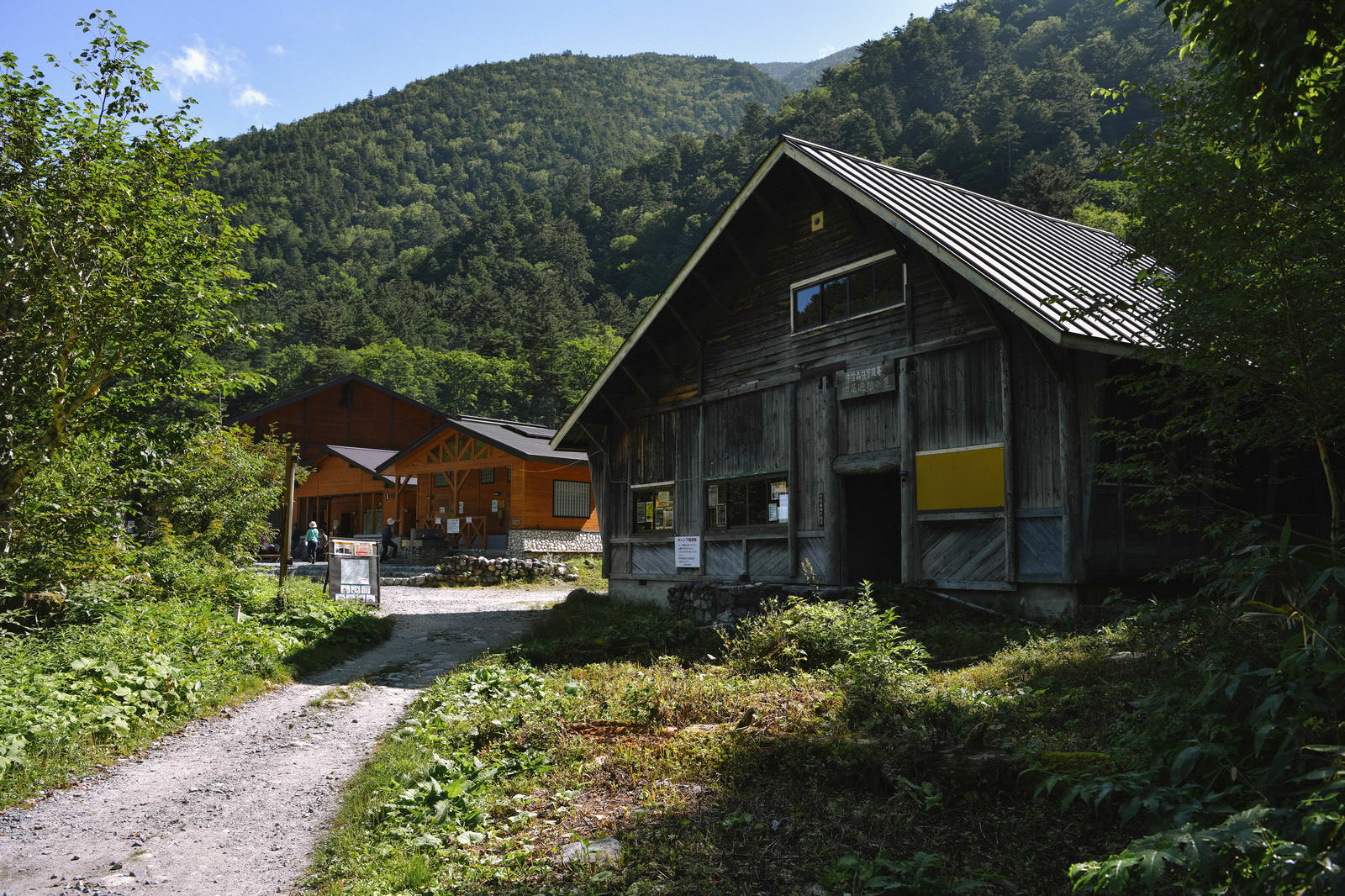 北アルプスの奥穂高岳登山道に建つ黒い木造の山小屋と周囲の雑木林