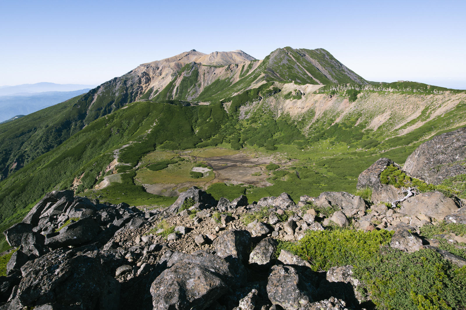 御嶽山の四ノ池とクレーター状の火口地形、溶岩と高山植物が分布する山岳風景