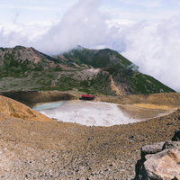 御嶽山の二ノ池と赤い山小屋、硫黄の白濁した池と登山風景の写真