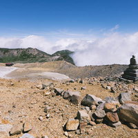 日本百名山・御嶽山の二ノ池畔に立つ仏像と山小屋の写真