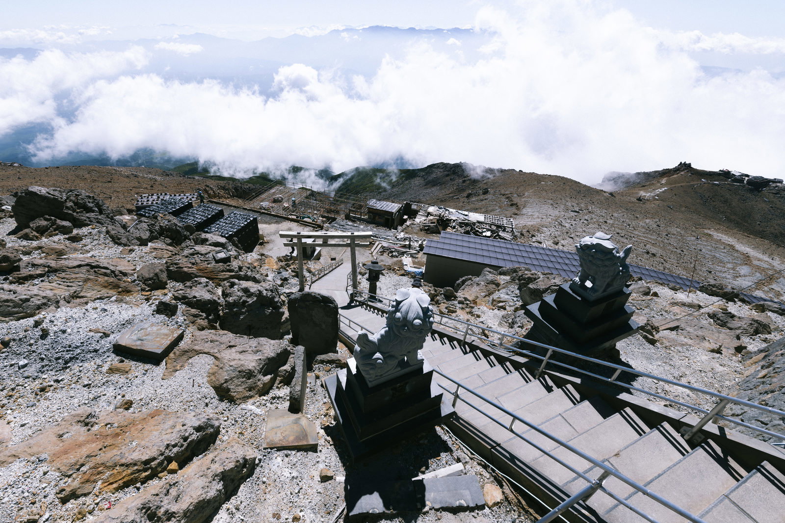 御嶽山山頂の鳥居と木製階段、雲海と岩場の登山道