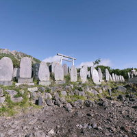 御嶽山登山道沿いに並ぶ歴史ある石碑と青空の写真