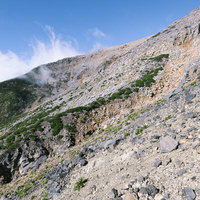 火山らしい景色が広がる御嶽山の登山道を進む登山者の風景の写真