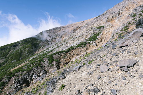 火山らしい景色が広がる御嶽山の登山道を進む登山者の風景