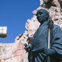 日本百名山・御嶽山の岩山に立つ覚明上人の像の写真