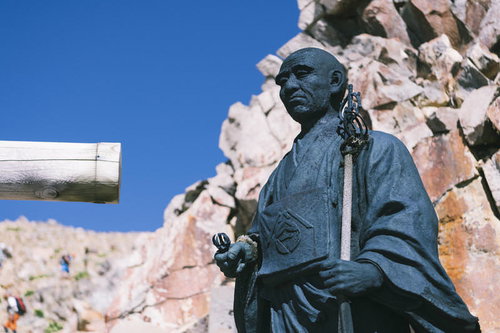 日本百名山・御嶽山の岩山に立つ覚明上人の像