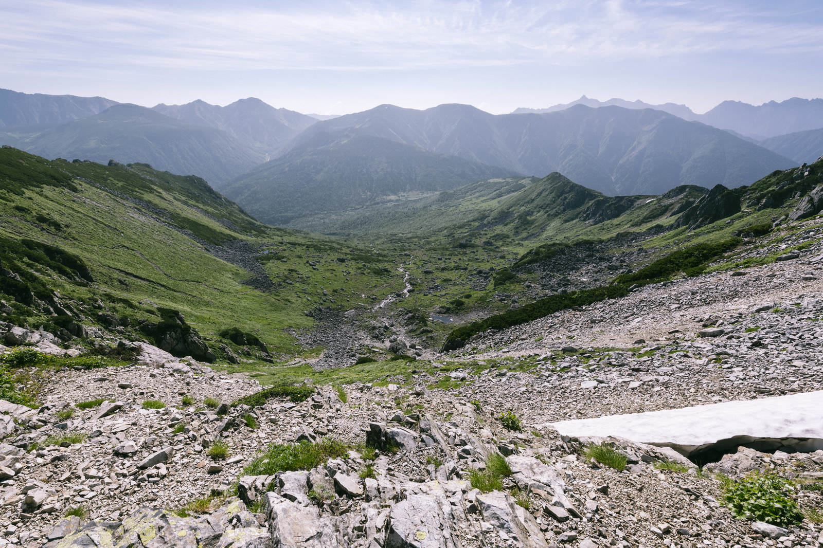 黒部五郎岳の巨大なカール地形。手前は礫地、奥は緑の谷と連なる山々