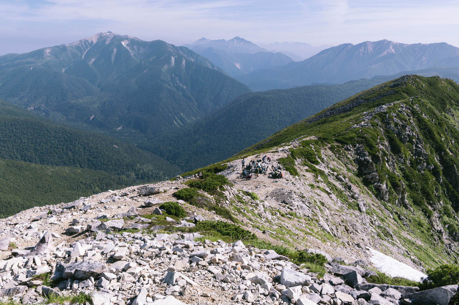 黒部五郎岳の登山道から見た立山方面の雄大な山並みと登山者たち