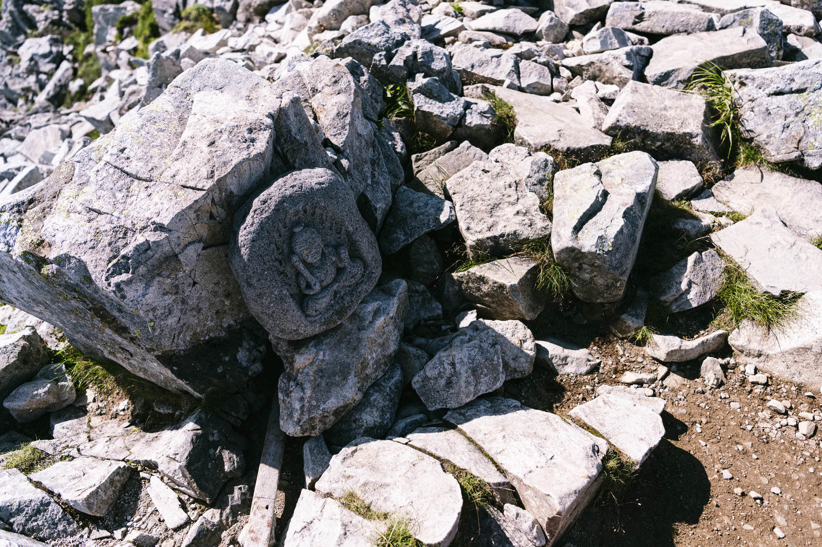 黒部五郎岳の山頂に祀られた石造りの仏像と岩場の風景