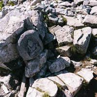 黒部五郎岳山頂に祀られた仏像と岩場の苔むした風景の写真