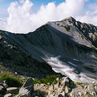 ガスから姿を現した北薬師岳の尾根と岩場の山頂風景の写真