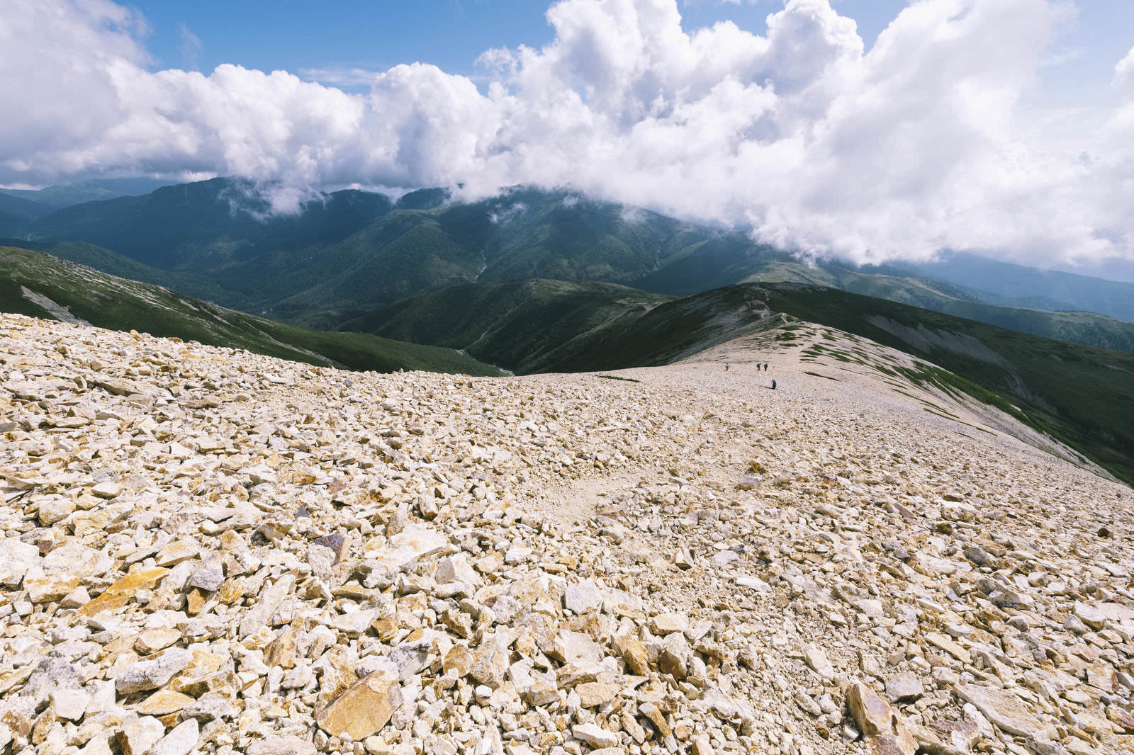 薬師岳の白い岩屑が広がるガレ場から見た雲がかかった山々の風景