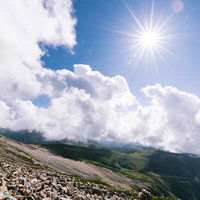 陽光と光芒が照り付ける薬師岳山頂のガレ場の写真