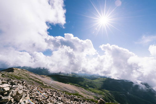 陽光と光芒が照り付ける薬師岳山頂のガレ場