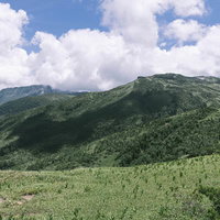 雲に覆われた薬師岳と黒部五郎岳の尾根を望む北アルプスの山岳風景の写真