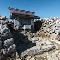 木曽駒ヶ岳山頂の岩場に建つ神社と登山道の風景の写真