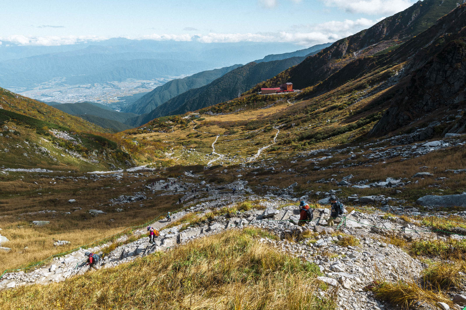 秋の千畳敷カールで草紅葉の中を歩く複数の登山者