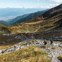 秋の千畳敷カールを下る登山者たちと草紅葉の景観の写真