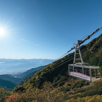 青空に光芒が映る、紅葉の木曽駒ヶ岳ロープウェイの写真