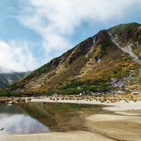 秋の濃ヶ池に映る雲と紅葉した木曽駒ヶ岳の山岳風景の写真