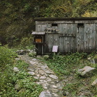 妙高山の河原の湯にある木造の小屋と露天風呂の写真