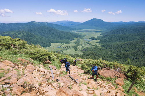 至仏山の岩場の登山道を歩く登山者と眼下の尾瀬