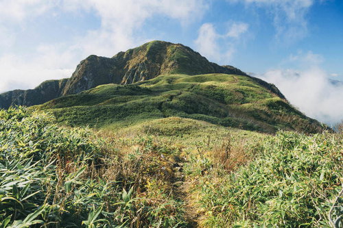 笹原の向こうに堂々と見える雨飾山の山容と登山道の風景