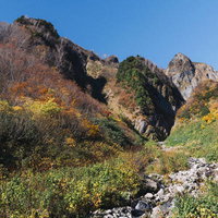 荒菅沢から見上げる紅葉に染まる雨飾山の秋景色の写真