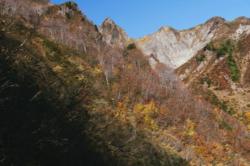 雨飾山の荒菅沢で色づく紅葉と険しい岩肌の渓谷美