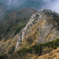 雨飾山山頂から見下ろす切り立った岩山と山稜線の写真