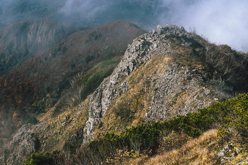雨飾山山頂から見下ろす切り立った岩山と山稜線
