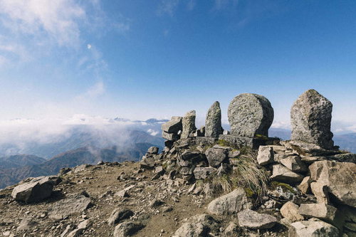 日本百名山・雨飾山山頂の岩場に立つ石仏と青空
