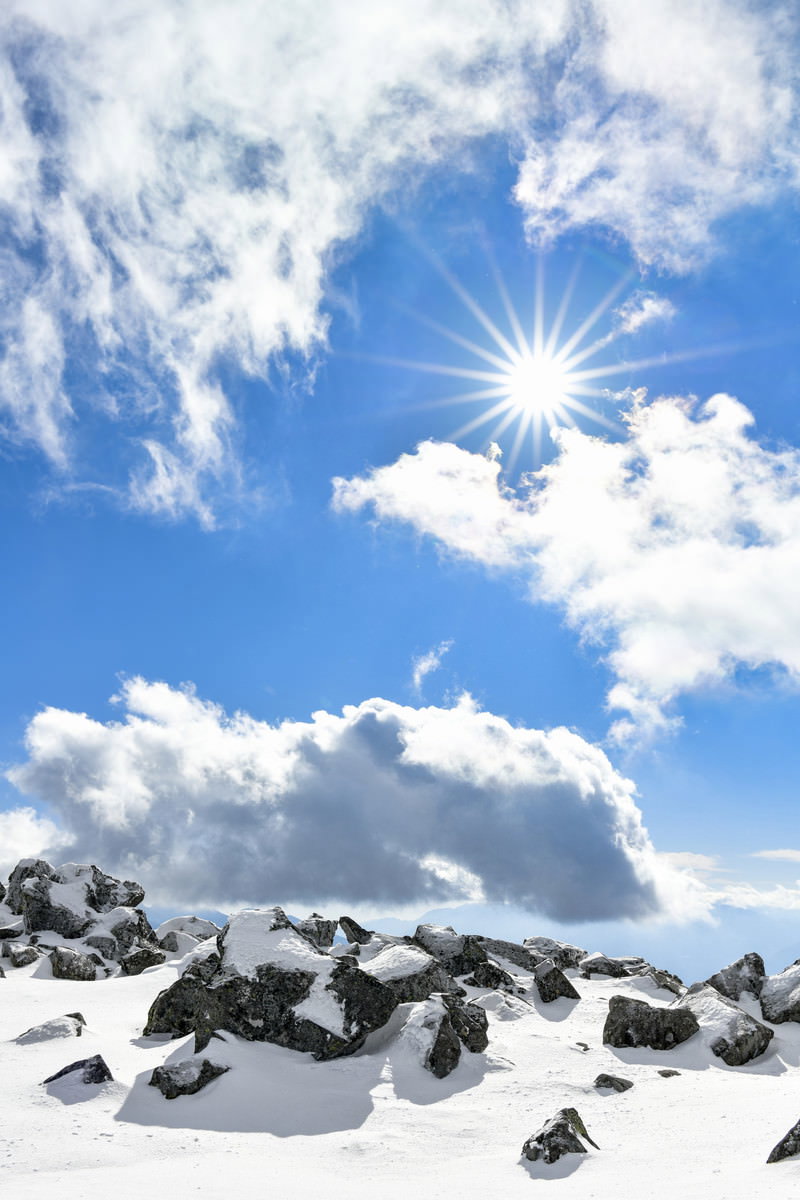 蓼科山山頂から見た太陽の光芒と雲海、残雪のある山頂風景