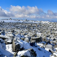 雪に覆われた蓼科山山頂の岩場と青空の写真