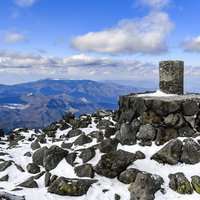 蓼科山山頂の石碑と美ヶ原の山々を望む冬景色の写真