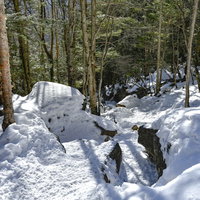 踏み固められた雪積もる蓼科山の登山道を進む登山者の冬山風景の写真