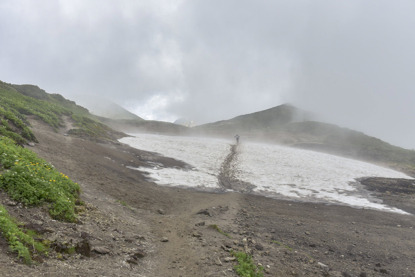 霧に包まれた山の稜線を歩く登山者の後ろ姿