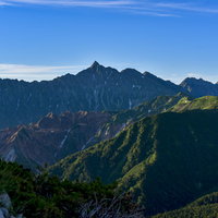 朝日を受けて浮かび上がる槍ヶ岳と裏銀座の山並みの写真