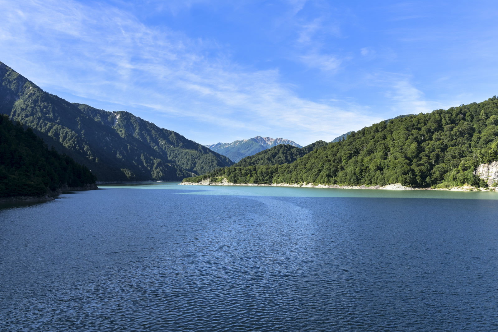 青い湖面の黒部湖と背景にそびえる立山連峰の山々