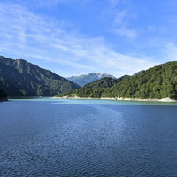 巨大な黒部湖の向こうに立つ赤牛岳と立山連峰の写真
