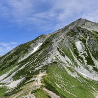 浄土山鞍部から見上げる立山雄山と青空の山岳風景の写真