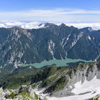 立山から見下ろすエメラルドグリーンの黒部湖と山々の写真