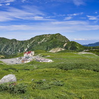 立山室堂の高原に立つホテルと奥大日岳方面の風景の写真