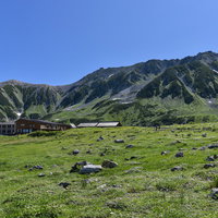 立山室堂の高原に建つ山荘と日本百名山の雄山の写真