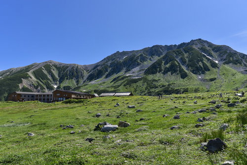 立山室堂の高原に建つ山荘と日本百名山の雄山