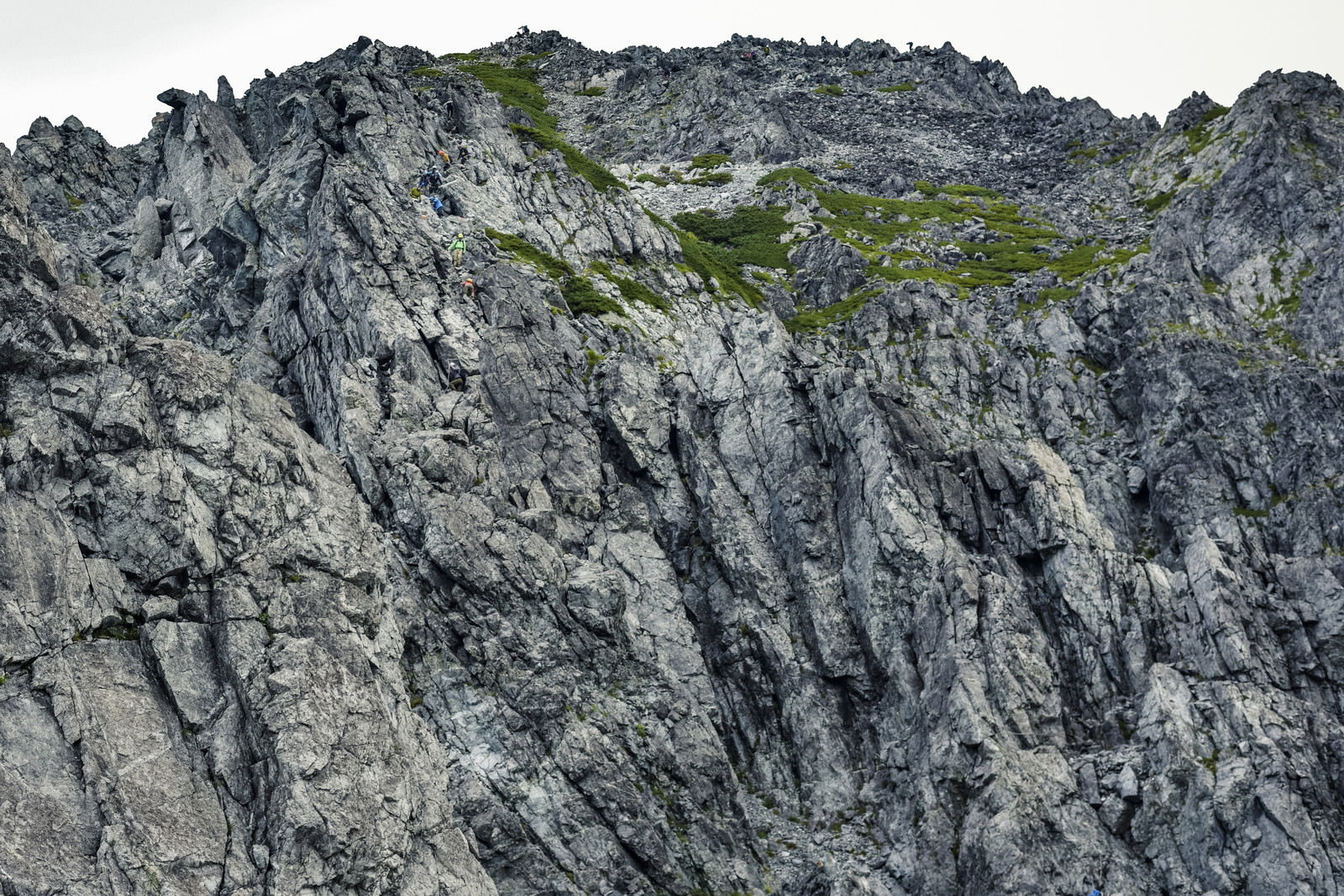 険しい灰色の岩稜を登る登山者の姿