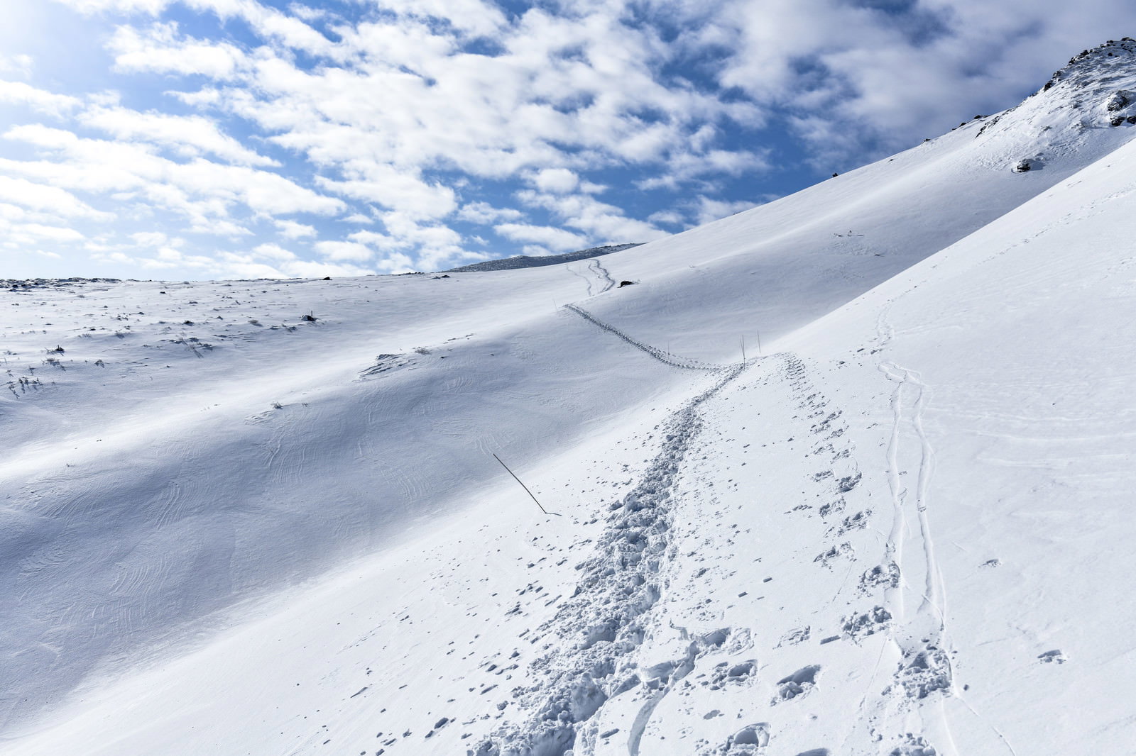 雪に覆われた安達太良山の斜面に一筋のトレースが続く冬山の風景