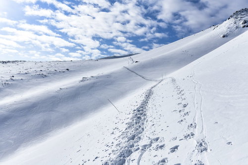 冬の安達太良山の積雪した斜面に続くトレースと足跡