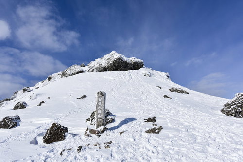 冬の安達太良山山頂に立つ山頂標と青空